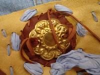 gold metal coin laced in silk on deer leather